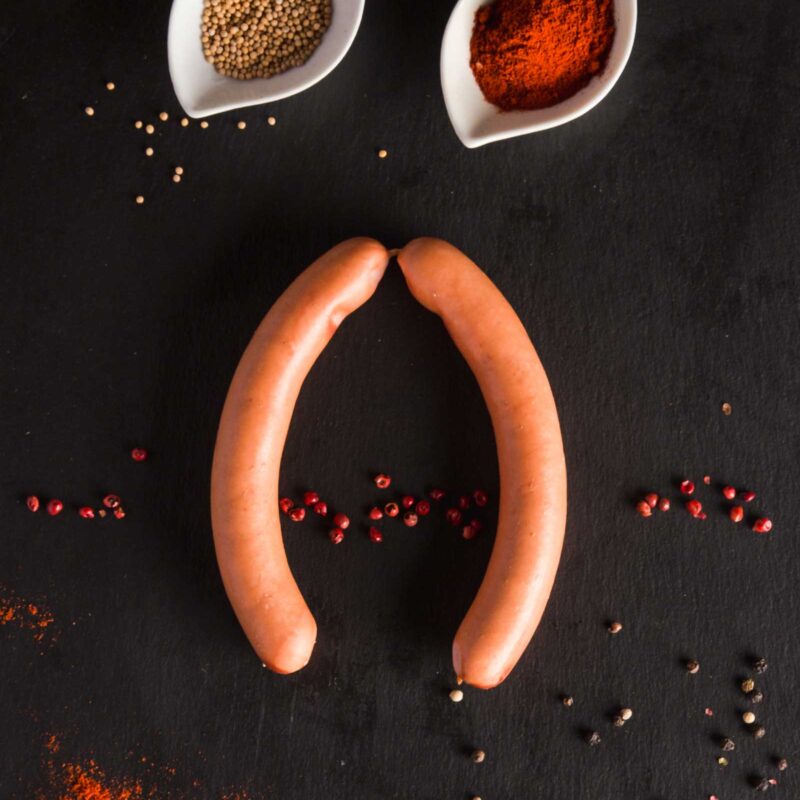 Zwei Würstchen mit Gewürzen.
