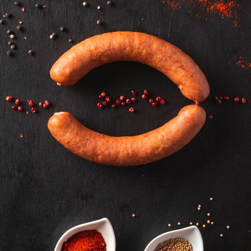 Wurst mit Gewürzen auf schwarzem Hintergrund
